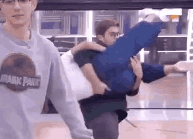 a man is carrying a woman on his back while another man looks on .
