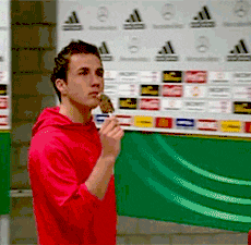 a man in a red hoodie is eating an ice cream cone in front of an adidas wall
