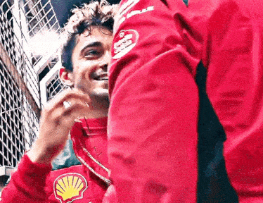 a man in a red jacket is smiling while standing next to another man in a red jacket .