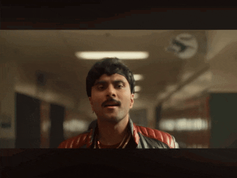a man with a mustache is standing in a hallway with a clock that says s on it