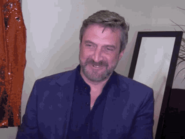 a man with a beard wearing a blue suit is smiling