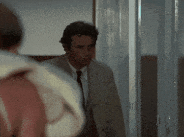 a man in a suit and tie is walking through a hallway