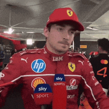 a man wearing a red ferrari jacket and a red hat with an ibm logo