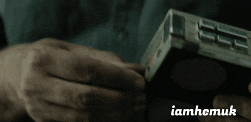 a close up of a person holding a device with the word iamhemuk written below it