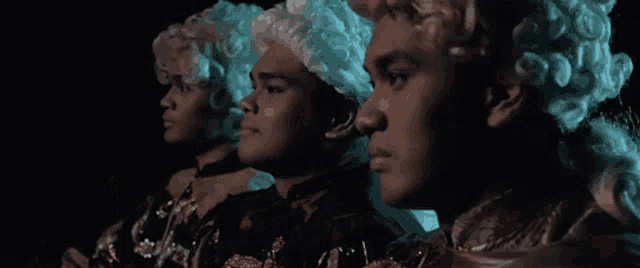three men wearing wigs are standing next to each other in a dark room