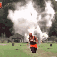 a woman is running in a field with smoke coming out of the ground