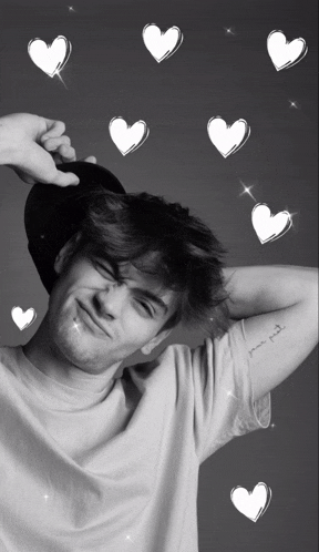 a black and white photo of a young man with hearts around him and a tattoo on his arm that says your first