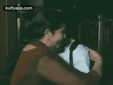 a man and a woman are hugging each other in a room .