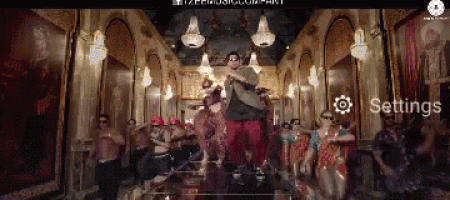a group of people are dancing in a room with a settings button on the bottom