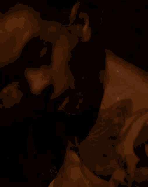 a man with a tattoo on his chest is smoking a cigarette in the dark .