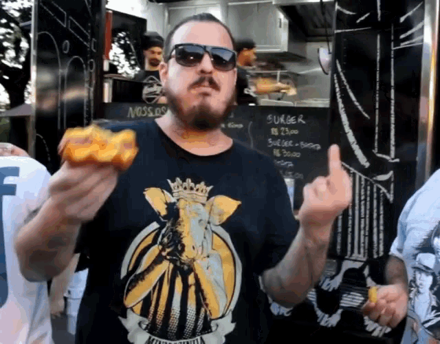 a man with a beard wearing sunglasses and a black shirt with a king on it