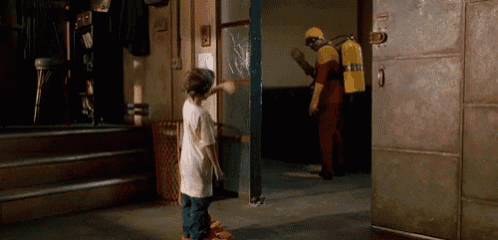 a man with a fire extinguisher on his back is standing next to a boy in a room