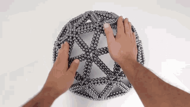 a person is playing with a sphere made of magnets .