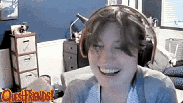 a woman wearing headphones is smiling in front of a questfriends logo