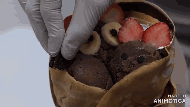 a person is putting strawberries and bananas on top of ice cream