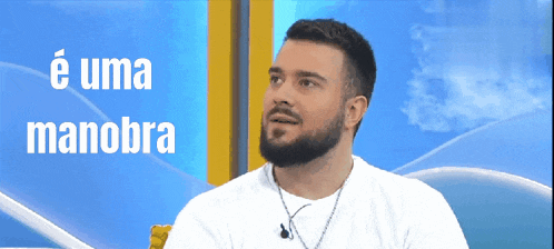 a man with a beard is sitting in front of a screen that says e uma manobra