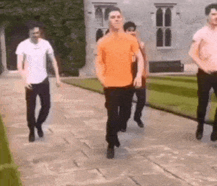 a group of young men are walking down a sidewalk next to a building .