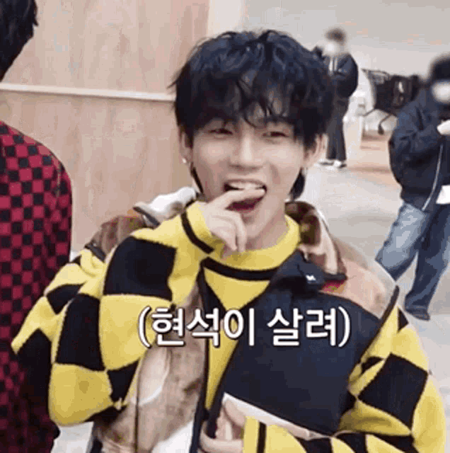 a young man wearing a yellow and black checkered sweater is eating a snack .