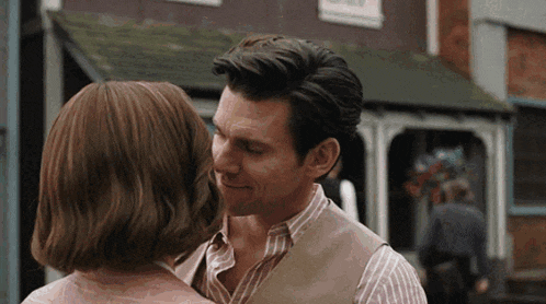 a man and a woman are hugging and kissing in front of a building