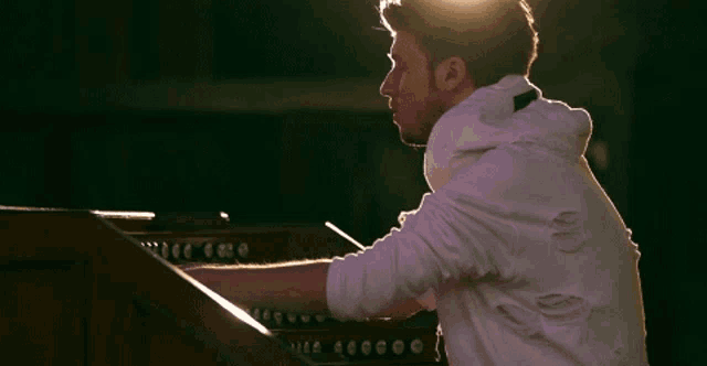 a man in a white jacket is playing a keyboard