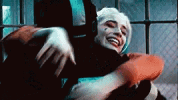 harley quinn is hugging the joker in a room .