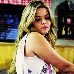 a woman with blonde hair is wearing a white tank top