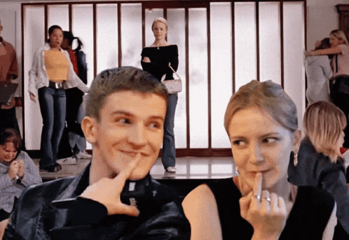 a man and a woman are posing for a picture and the woman is covering her mouth with her finger