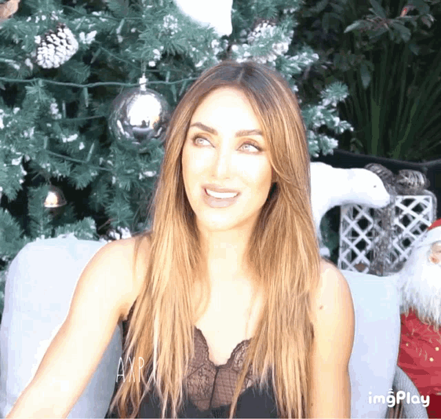 a woman sitting in front of a christmas tree with an imgplay watermark