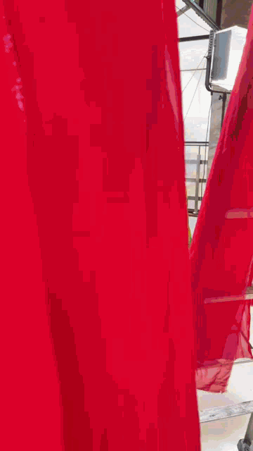 a woman in a yellow dress is standing on a balcony with a red curtain behind her