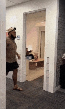 a man in a brown shirt and black shorts is standing in a hallway