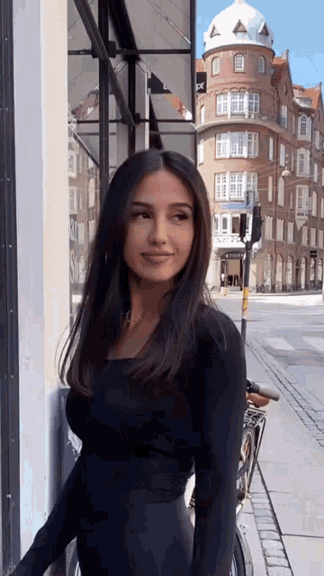 a woman in a black top stands in front of a building that says ' se '