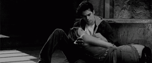 a black and white photo of a man and a woman sitting on the ground .