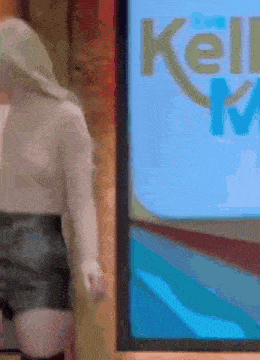 a woman is standing in front of a screen that says kelly marie on it .
