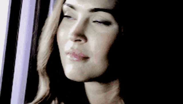 a close up of a woman 's face looking out a window