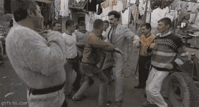 a group of men are dancing on a street with a gifbin.com watermark in the corner