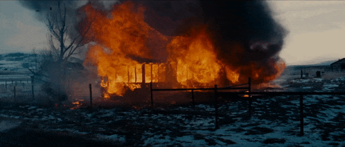 a house is burning in the middle of a field