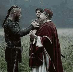 a man in a red cape shakes hands with another man in a black shirt