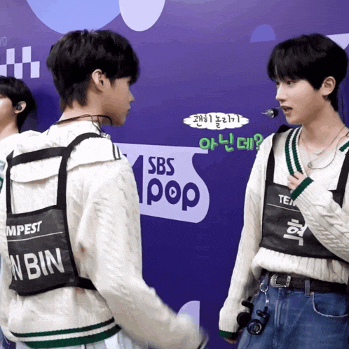two boys are standing in front of a sbs pop logo