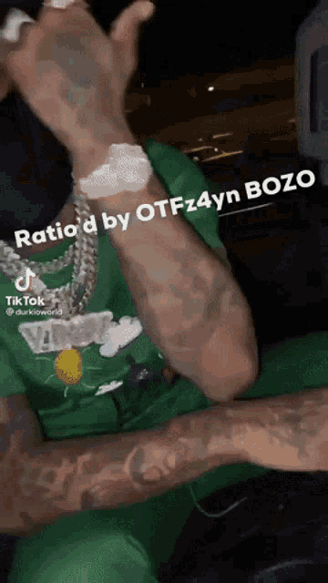 a man with a lot of tattoos on his arms is wearing a green shirt and a watch .