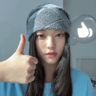 a woman wearing a hat and a blue shirt gives a thumbs up