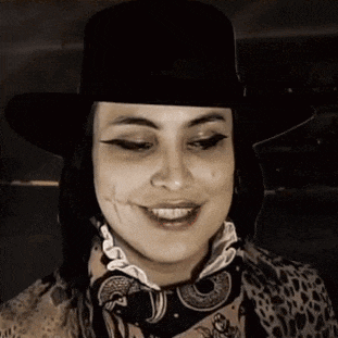 a woman wearing a hat and scarf is smiling in a black and white photo