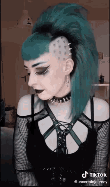 a woman with blue hair is wearing a black top and a choker ..