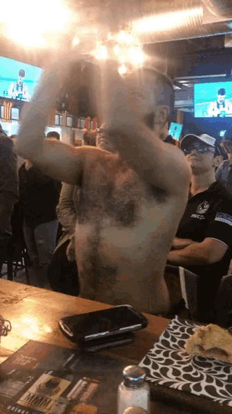 a man without a shirt is sitting at a table with a phone on it