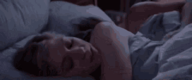 a man and a woman are kissing on a bed in the dark .