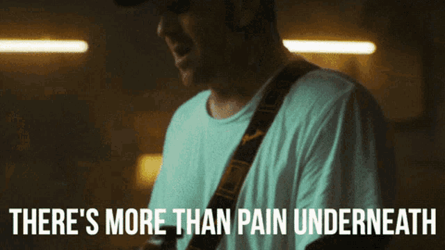 a man playing a guitar with the words there 's more than pain underneath below him