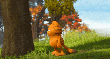 a cartoon character named garfield is standing in the grass near a tree