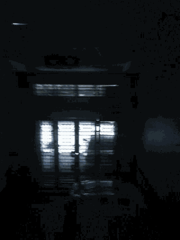 a dark hallway with a light shining through the window