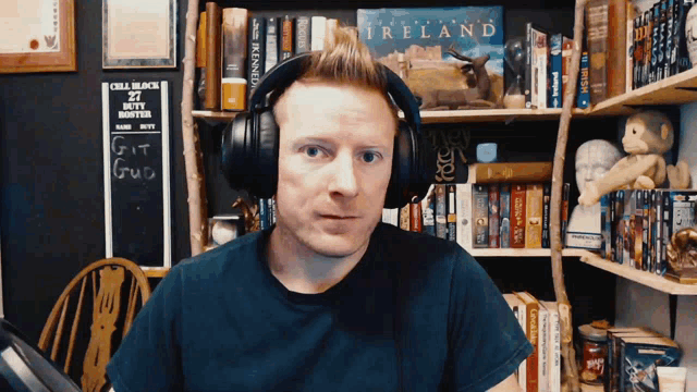 a man wearing headphones stands in front of a bookshelf with a sign that says ireland on it