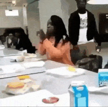 a man and a woman are sitting at a table with a carton of milk on it .