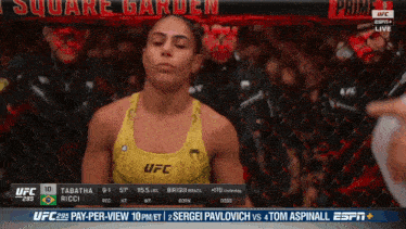 a woman in a yellow tank top with ufc on it